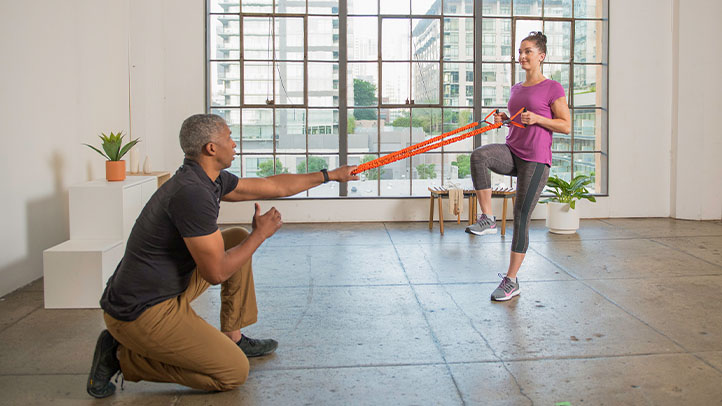 Trainer assisting client with resistant band