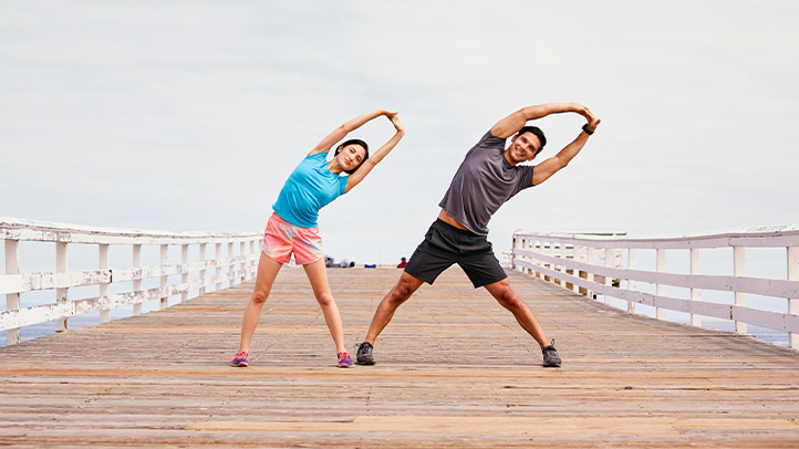 Woman and man stretching on board walk